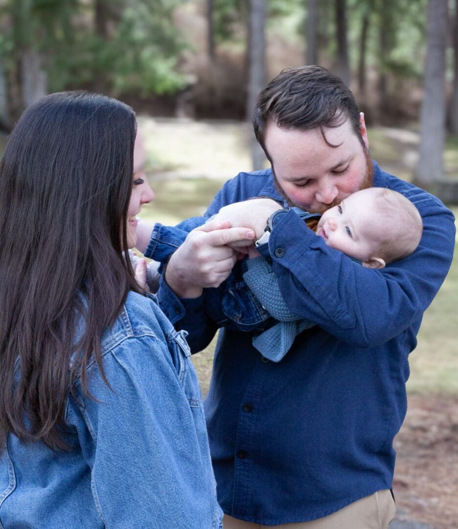 A father playfully holding his baby while the mother watches.