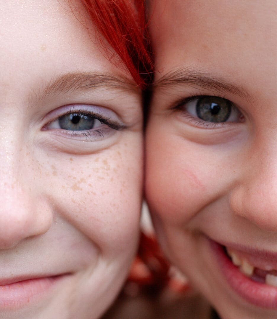 Close-up of two smiling children with red hair and freckles.