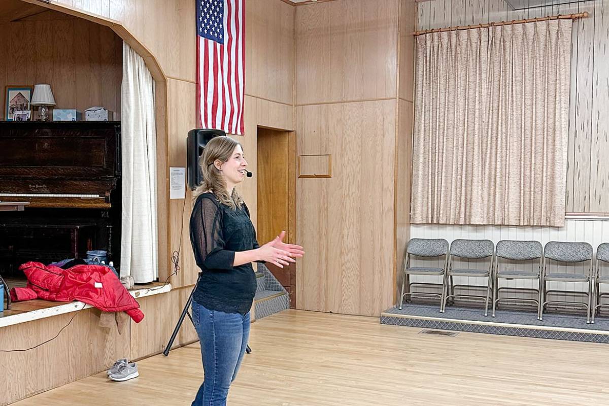 Woman clapping in a room with an American flag and chairs.