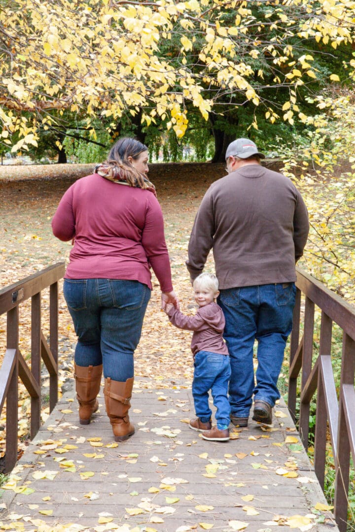 Family walking on a wooden bridge in autumn.