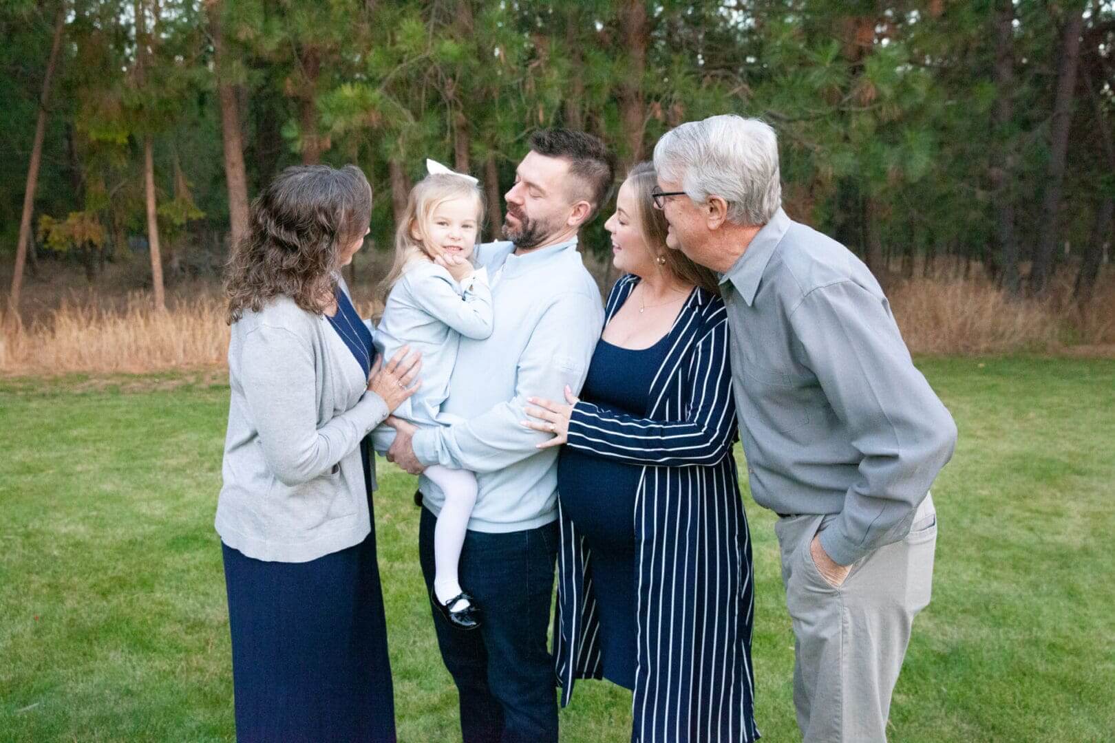 Family standing together outdoors, smiling warmly.