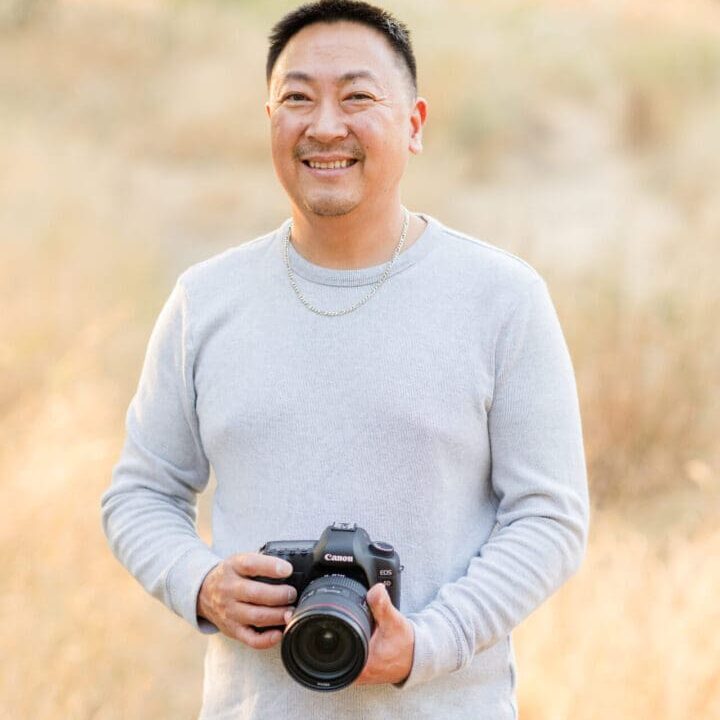 Man holding camera in a grassy field.